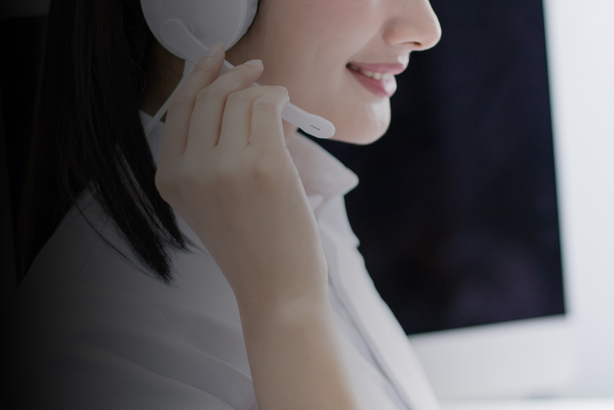 Smiling Asian businesswoman consultant wearing microphone headset of customer support phone operator at workplace.
